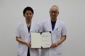 佐久医療Ｃ肝胆膵施設認定　認定書を掲げる渡辺院長（右）と坂本部長
